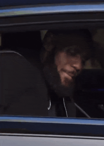 a person is sitting in a car with their head out the window