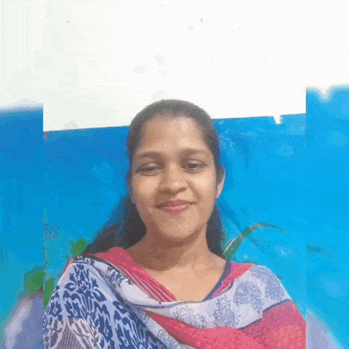 a woman in a colorful dress is smiling in front of a blue background .