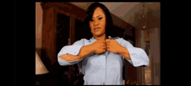 a woman in a blue shirt is adjusting her shirt