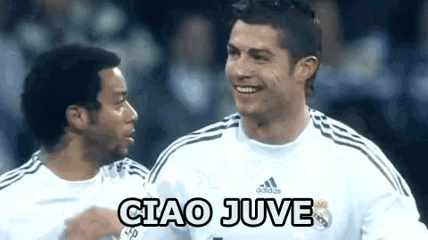 a soccer player is smiling and talking to another player while wearing a white adidas shirt .