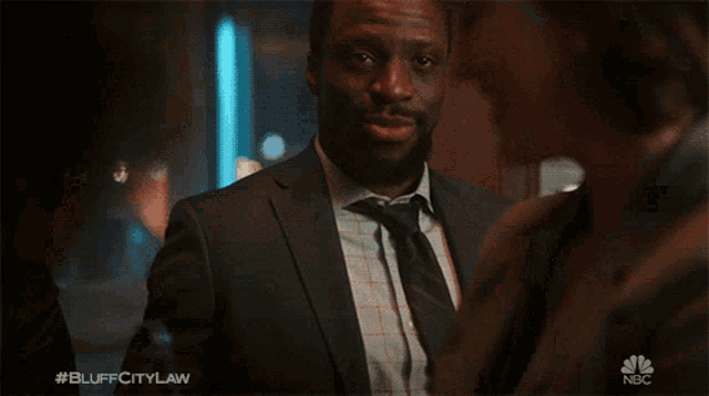 a man in a suit and tie is talking to a woman with #bluffcitylaw written below him