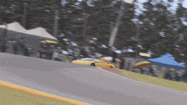 a yellow sports car is driving on a track