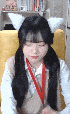 a girl wearing white ears and a red lanyard is sitting in a chair