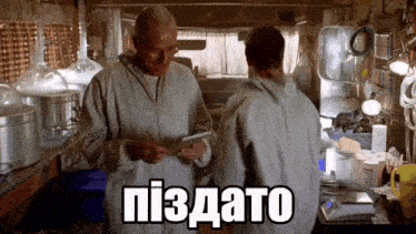 two men are standing next to each other in a room and one of them is holding a tablet and the other is holding a pen