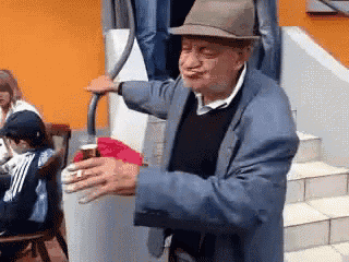 a man wearing a hat and a suit is holding a bottle of beer