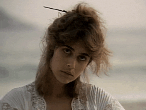 a woman with a hair pin in her hair looks at the camera with a serious look on her face