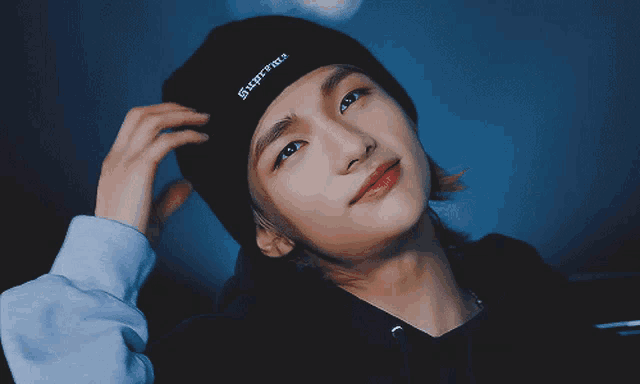 a person wearing a black beanie that says supreme
