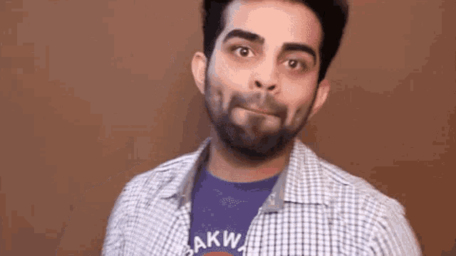 a man with a beard is making a funny face and wearing a t-shirt that says sakw .