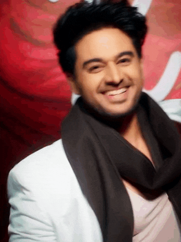 a man wearing a white jacket and a scarf smiles for the camera