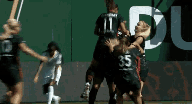 a group of female soccer players celebrate a goal with a sign in the background that says du