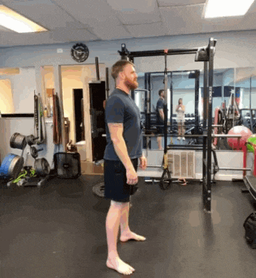 a man is doing squats in a gym with a woman in the background .