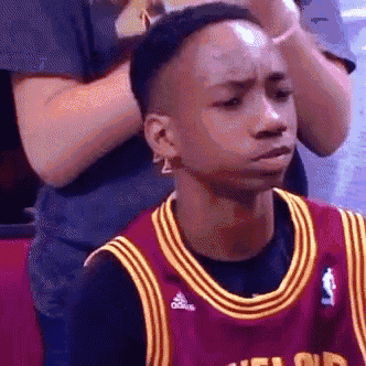 a young man wearing a basketball jersey is sitting in the stands .