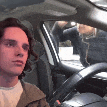 a man sitting in a car with a potted plant in the background