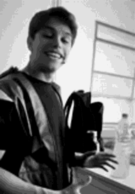 a young man is smiling while holding a cup of coffee