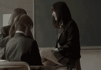 a person is standing under a desk in a classroom with a hook hanging from it .