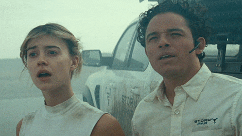 a man and a woman are standing in front of a truck that says storm par on it