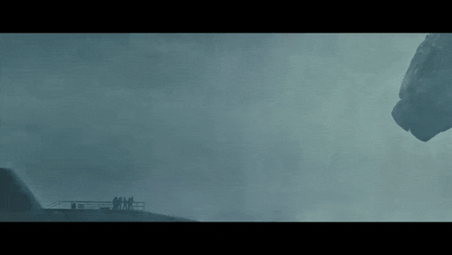 a group of people are standing on top of a building looking at a large rock in the sky .