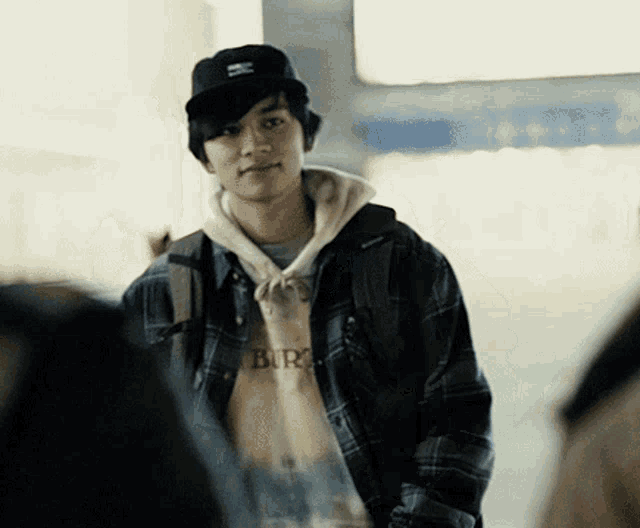 a man wearing a plaid jacket and a hoodie that says burg on it