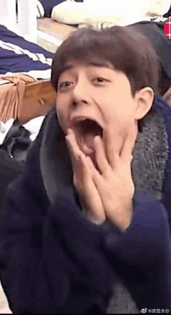 a young man with his mouth open is making a funny face .