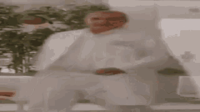 a man in a white lab coat and white pants is walking in a hallway .
