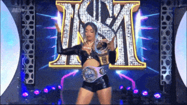 a woman is holding a world heavyweight championship belt in front of a sign that says ism