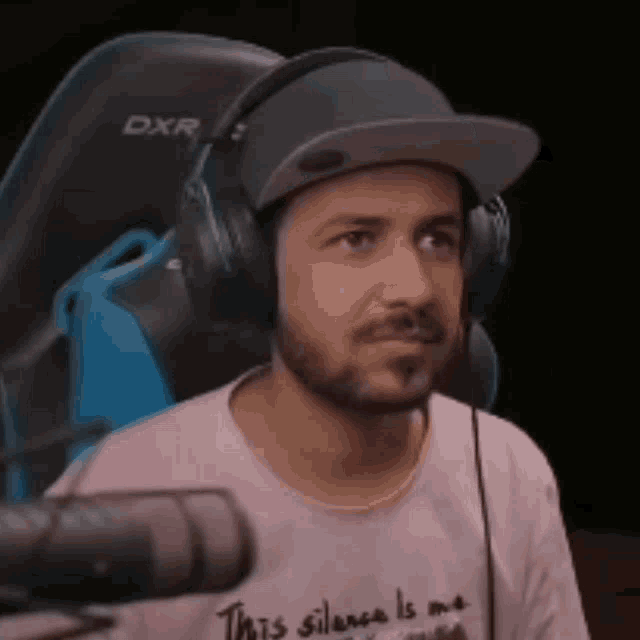a man is wearing headphones and a hat while sitting in a chair .