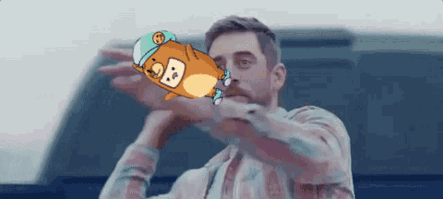 a man in a plaid shirt is holding a cartoon character with the letter g on it