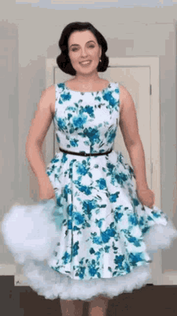 a woman in a blue and white floral dress is standing in a room .