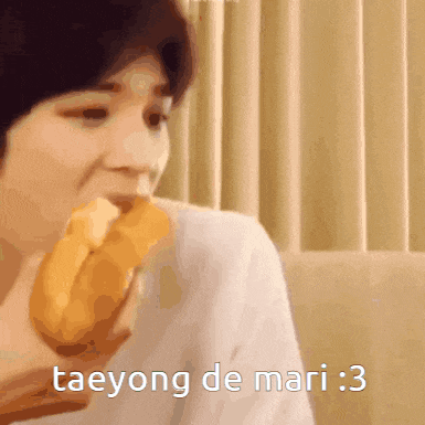 a person eating a sandwich with the words taeyong de mari