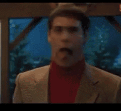 a man in a suit and a red turtleneck is sticking his tongue out