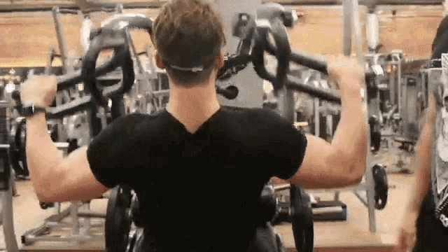 a man is using a machine in a gym to lift weights .
