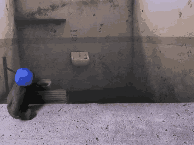 a blue ball is sitting in a dark room with graffiti on the wall that says " knee "