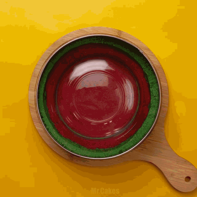 a bowl of red and green powder sits on a wooden cutting board with the words mr cakes written on the bottom