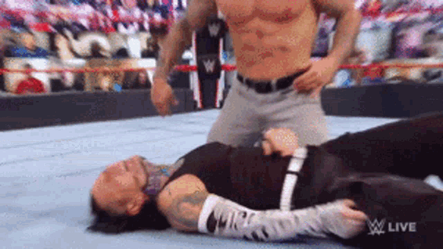 a wrestler is laying on the ground while another wrestler is kneeling over him