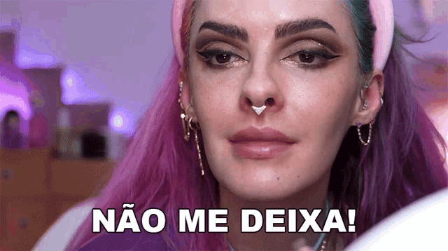 a woman with purple hair and a nose ring is making a funny face and says não me deixa !