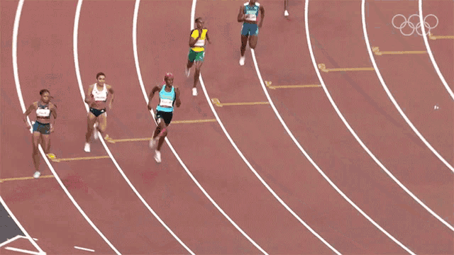 a group of female athletes are running on a track with the olympics logo in the background