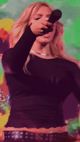 a woman in a black top is holding a microphone in her hand