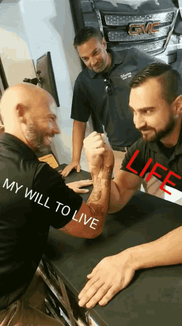 two men arm wrestling with one wearing a shirt that says ' my will to live ' on it