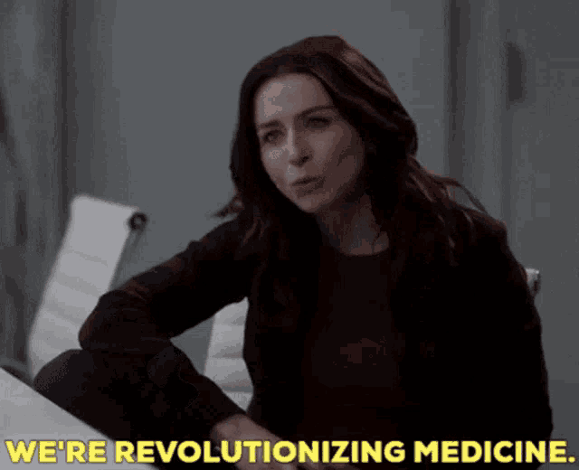 a woman sitting at a table with the words we 're revolutionizing medicine behind her