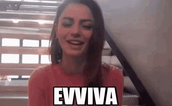 a woman in a red sweater is smiling and says eviva in white letters .