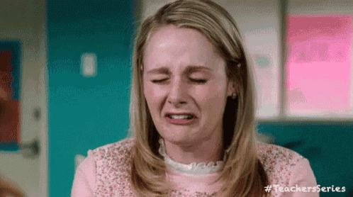 a woman in a pink shirt is crying and making a funny face with her eyes closed .