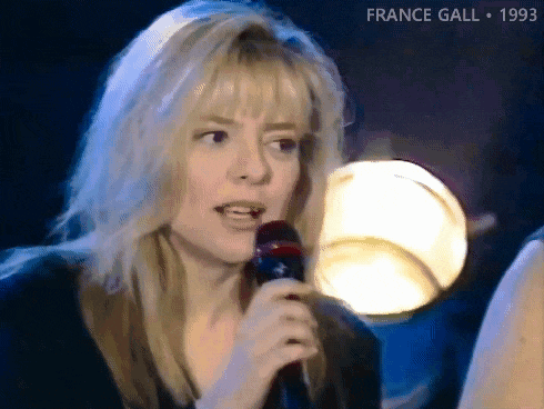 a blonde woman singing into a microphone with the year 1993 on the bottom right