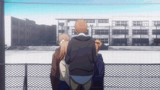 a group of people standing in front of a fence looking at a building