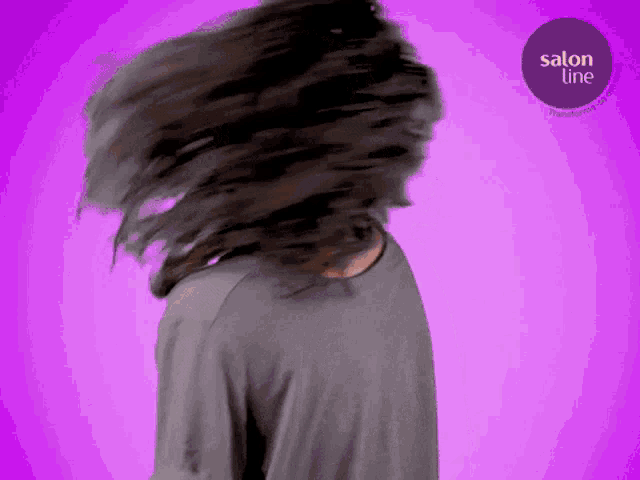a woman 's hair is blowing in the wind with a salon line logo behind her
