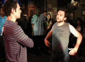 a man in a striped shirt stands next to another man in a gray tank top