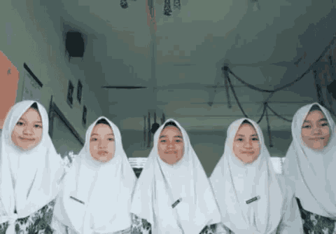 a group of girls wearing white hijabs are standing in a row