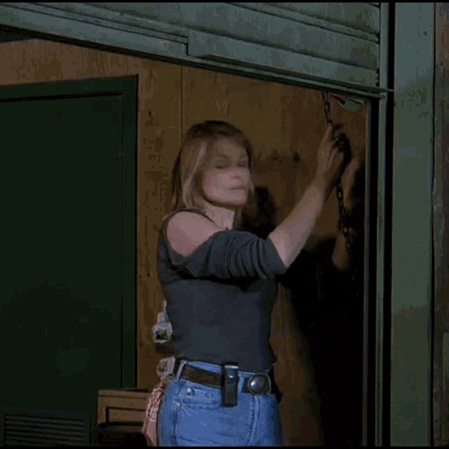 a woman in a gray shirt and jeans is holding a chain