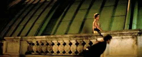 a man and a woman are standing on a balcony at night