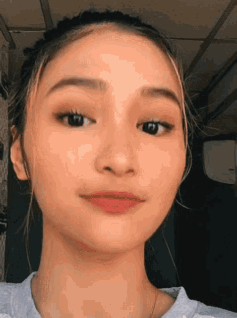 a close up of a girl 's face with a gray shirt on