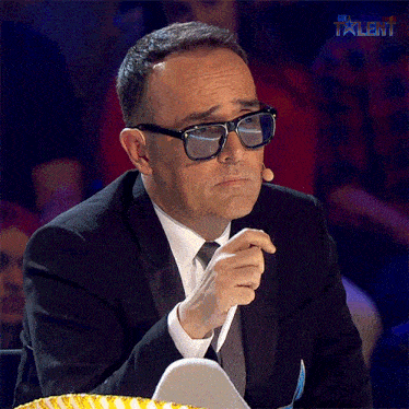 a man wearing glasses and a suit is sitting in front of a microphone with the word talent behind him